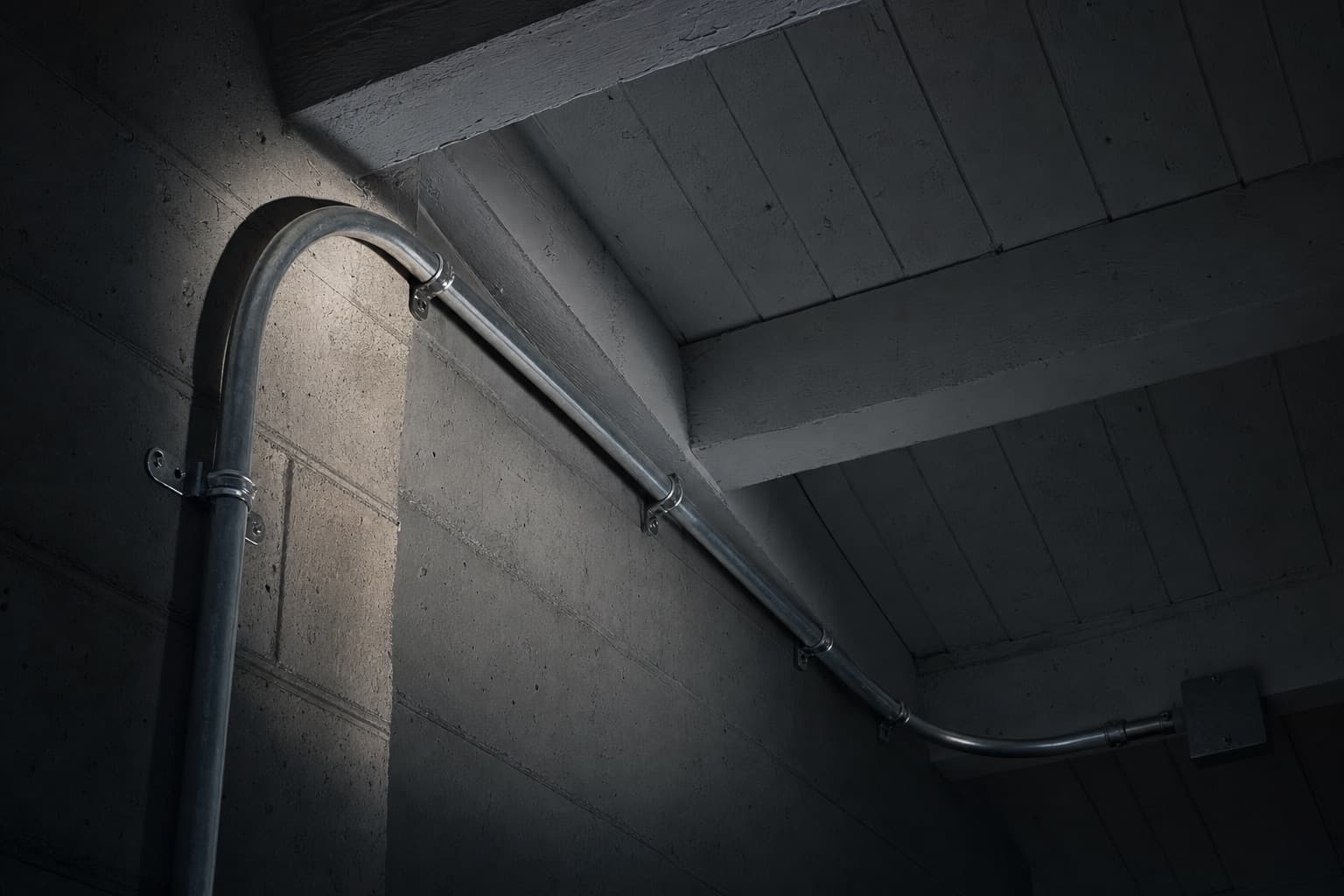 Rigid metal conduit sweeping through a long radius bend where a garage wall meets the ceiling